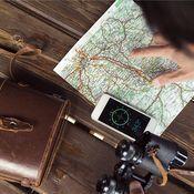 Auf einem Holztisch liegen eine Karte, ein Smartphone mit Kompass-App und ein Fernglas, daneben eine braune Ledertasche.